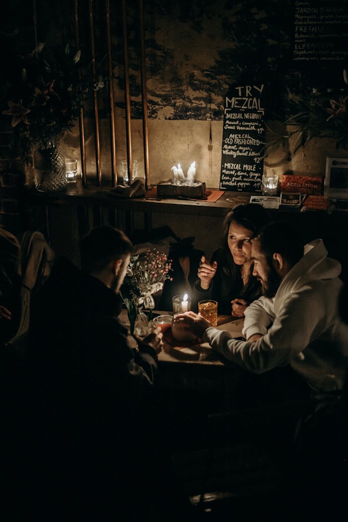 about-us A group of friends enjoying a warm evening in a candlelit cafe. Perfect for cozy lifestyle themes.